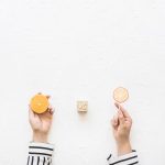 businesswoman-s-hand-holding-citrus-slice-versus-lollipop-white-background-scaled
