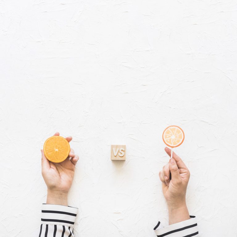 businesswoman-s-hand-holding-citrus-slice-versus-lollipop-white-background-scaled