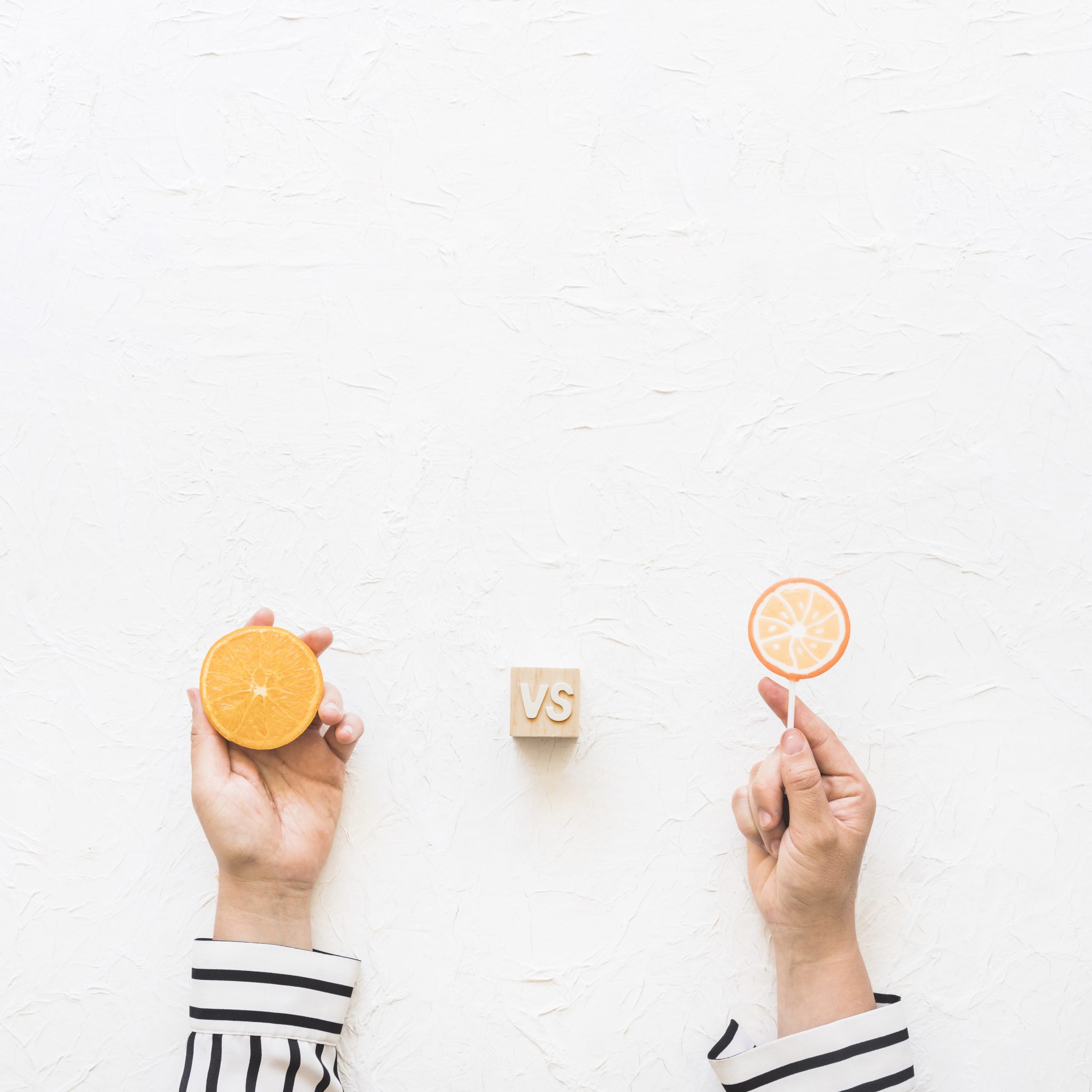 businesswoman-s-hand-holding-citrus-slice-versus-lollipop-white-background-scaled